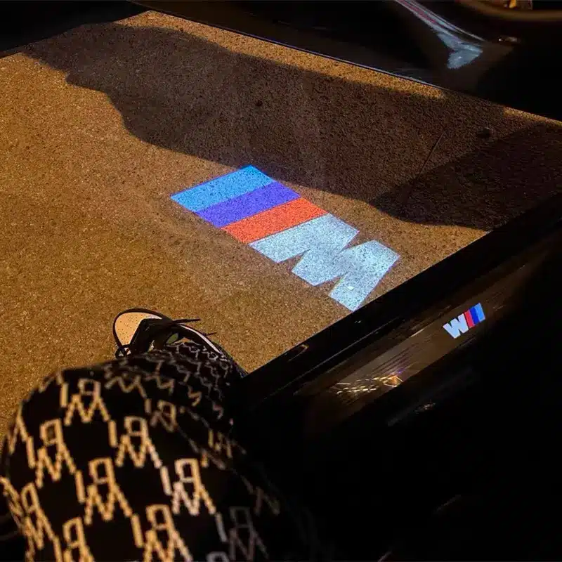 BMW M Puddle Lights BMW M puddle lights projecting logo onto ground beside car door in UK night setting