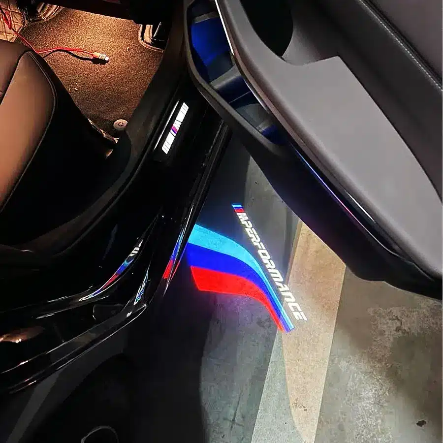 M Sport Puddle Lights A detailed view of the BMW logo on a car door, highlighting the brand's distinctive emblem and automotive excellence.